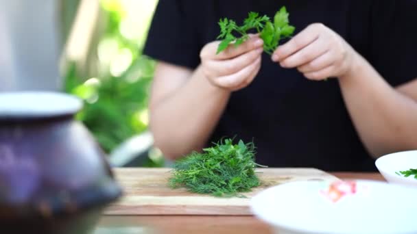 Close up of women's hands plucks greens from sticks and puts them on cutting board - Πλάνα, βίντεο