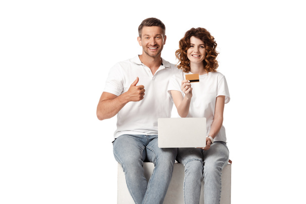 χαρούμενος άνθρωπος δείχνει τον αντίχειρα επάνω, ενώ σγουρά γυναίκα κρατώντας πιστωτική κάρτα κοντά στο φορητό υπολογιστή που απομονώνονται σε λευκό  - Φωτογραφία, εικόνα