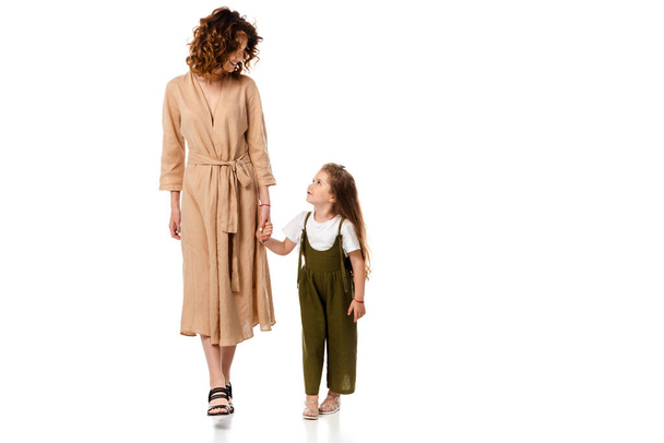 cheerful mother and adorable daughter holding hands isolated on white  - Photo, Image