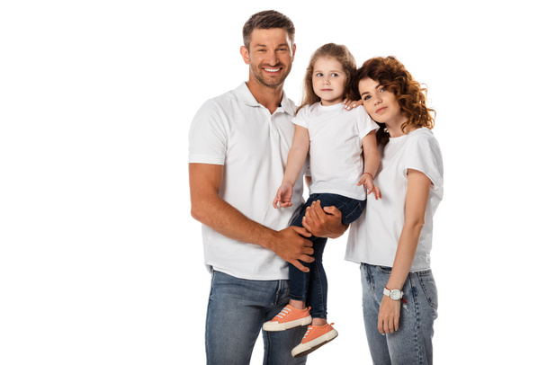cheerful father holding in arms cute daughter and standing with curly wife isolated on white - Фото, изображение