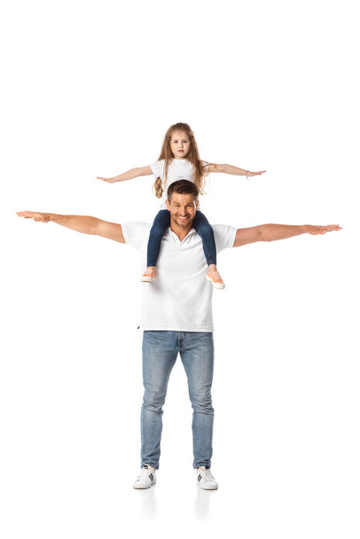 schattig kind met uitgestrekte handen zitten op schouders van vrolijke vader op wit  - Foto, afbeelding