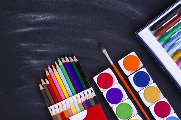 Set acquerello colorato, pastelli e matite su fondo nero polveroso gesso con pennello. - Foto, immagini