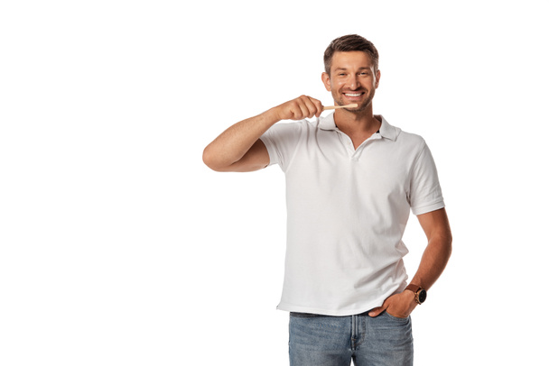 hombre alegre sosteniendo el cepillo de dientes y de pie con la mano en el bolsillo aislado en blanco
  - Foto, Imagen