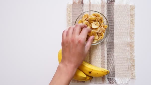 Syö kuivattuja banaanisipsejä. Käsitys terveellisestä ruoasta, terveellisestä elämäntavasta. ylhäältä näkymä tasainen lay - Materiaali, video