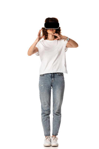 curly woman in virtual reality headset gesturing on white  - Φωτογραφία, εικόνα