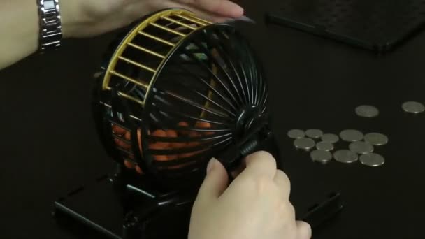Las manos rodando la jaula de bolas de bingo
 - Metraje, vídeo