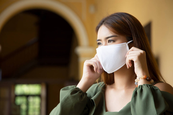 женщина в маске для лица, наблюдая новые нормальные социальные меры дистанцирования, чтобы сгладить кривую и предотвратить вирусную инфекцию, принимая физическое расстояние, покрывая лицо, рот и нос с помощью маски
 - Фото, изображение
