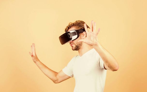 Explore cyber space. Man hipster virtual reality headset on peach background. Entertainment and education. Virtual communication. Virtual simulation. Man play game in VR glasses. Augmented 3D world - Φωτογραφία, εικόνα