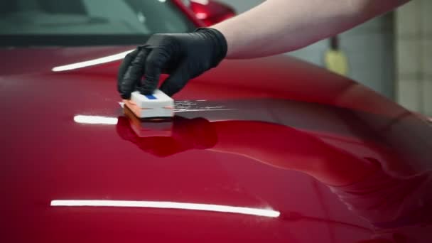 Man werknemer van auto detaillering studio het aanbrengen van keramische coating op auto verf met spons applicator - Video