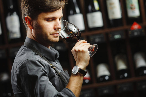 Bokal of red wine on background, male sommelier appreciating drink - 写真・画像