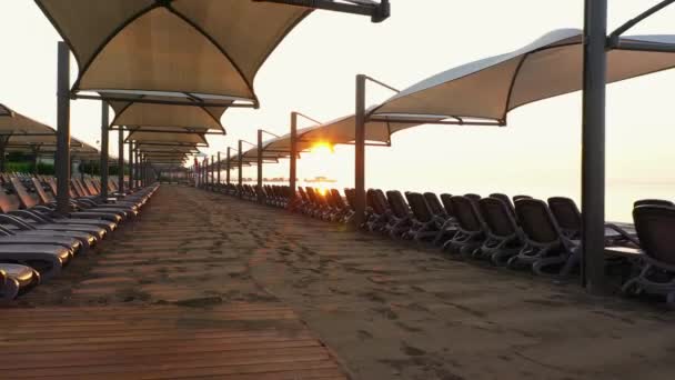 Strand ligbedden en parasols bij zonsondergang. - Video