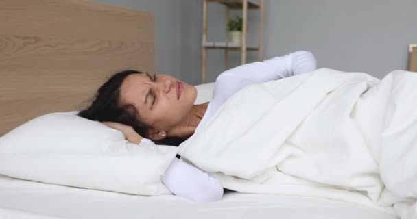 Upset woman waking up in bed feeling neck back pain - Felvétel, videó