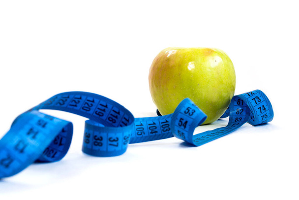 zöld alma és mérőszalag fehér háttérrel, fogyás és egészséges életmód - Fotó, kép