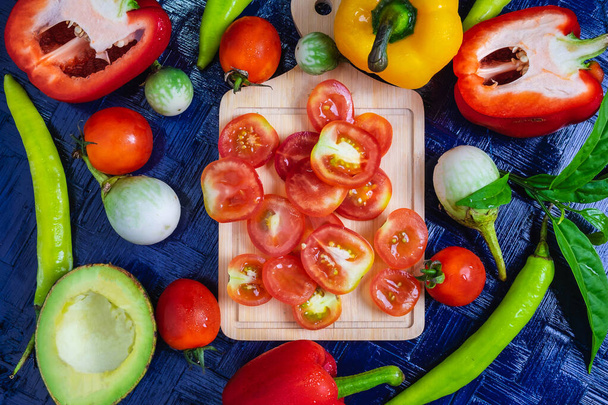 Fondo de tomate medio cortado y verduras saludables en tierra negra
 - Foto, imagen