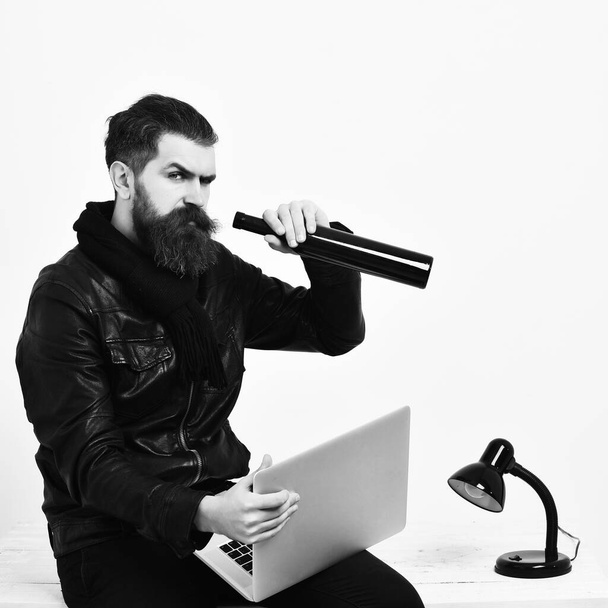 Bearded brutal caucasian hipster sitting on table with laptop - Photo, image