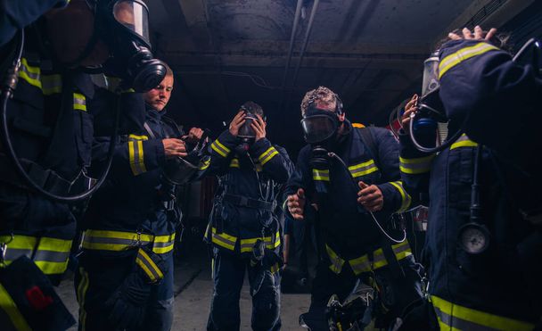 Ryhmä palomiehiä seisoo palokunnan sisällä kypärä ja suojaava univormu - Valokuva, kuva