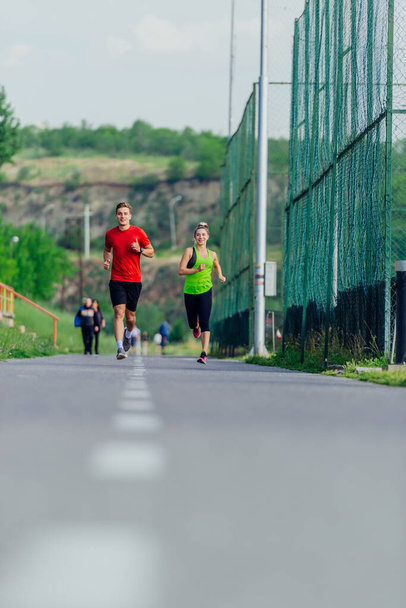 Young male and female athletes jogging and running on a road in the park - Photo, Image