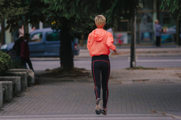 Привлекательная атлетическая девушка, занимающаяся спортом в городской местности днем - Фото, изображение
