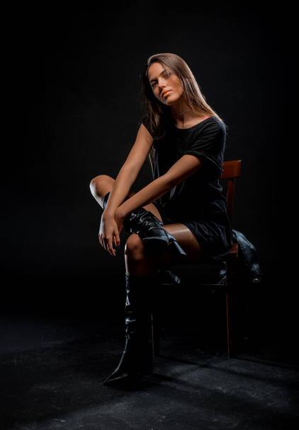 Studio body shot of a trendy young woman wearing modern style top and black boots - Foto, Imagen