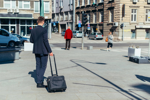 Joven hombre de negocios caminando con bolsa de viaje en la ciudad - Foto, imagen