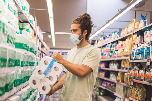 jovem comprando suprimentos em um supermercado com uma máscara médica
 - Foto, Imagem
