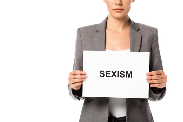 cropped view of businesswoman holding placard with sexism lettering isolated on white - Zdjęcie, obraz