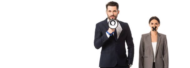 panoramic crop of businessman screaming in megaphone near businesswoman with duct tape on mouth isolated on white - Foto, Imagem