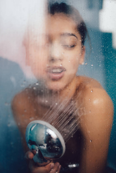 Beautiful woman behind the glass with water drops. - Foto, Bild