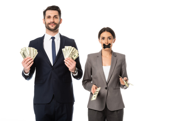 happy businessman holding dollars near businesswoman with duct tape on mouth isolated on white, gender inequality concept - Foto, afbeelding