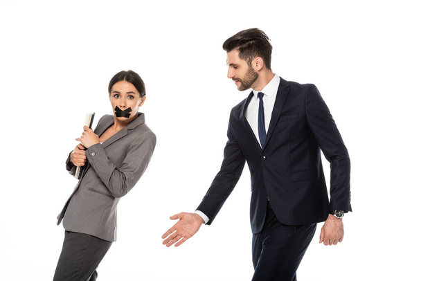 bearded businessman in formal wear molesting businesswoman with scotch tape on mouth isolated on white, sexual harassment concept   - Photo, Image