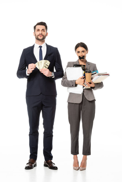 schöner Geschäftsmann hält Dollars in der Nähe von Geschäftsfrau mit Klebeband auf dem Mund auf weißem, Sexismus-Konzept  - Foto, Bild