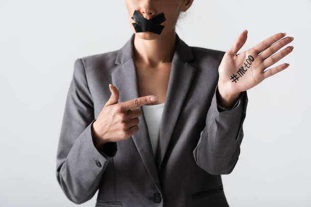 cropped view of businesswoman with scotch tape on mouth pointing with finger at hand with me too lettering isolated on white  - Photo, Image