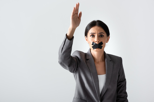 businesswoman with scotch tape on mouth raising hand and looking at camera isolated on white, gender inequality concept - Photo, Image