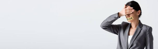 prise de vue panoramique de femme d'affaires avec lettrage sexisme sur ruban adhésif couvrant les yeux isolés sur blanc  - Photo, image