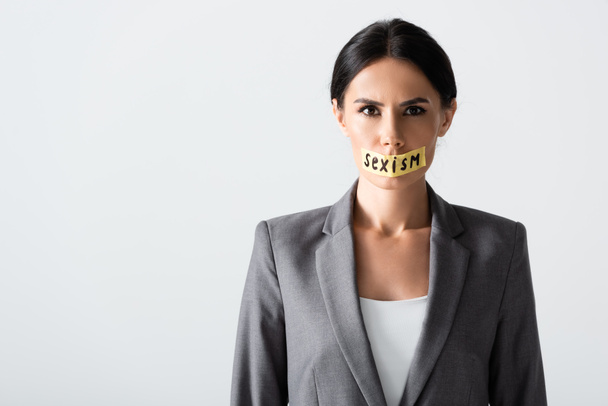 empresaria con letras de sexismo en cinta adhesiva mirando a la cámara aislada en blanco
  - Foto, imagen