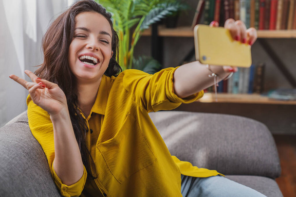 Beautiful brunette taking selfie with her smartphone at home - Foto, imagen