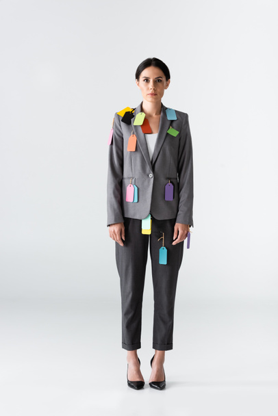 businesswoman z etykietami na formalnym ubraniu stojącym na białym, koncepcja nierówności płci  - Zdjęcie, obraz