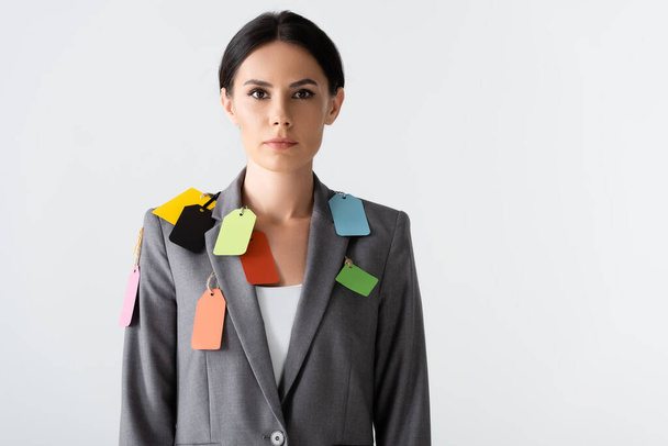 attraente donna d'affari con etichette su abbigliamento formale in piedi isolato su bianco, concetto di disuguaglianza di genere  - Foto, immagini