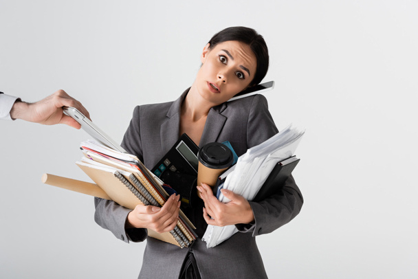 занятая деловая женщина держит калькулятор, бумажный стаканчик, документы, папки и ноутбуки во время разговора на смартфоне рядом бизнесмен изолирован на белом
  - Фото, изображение