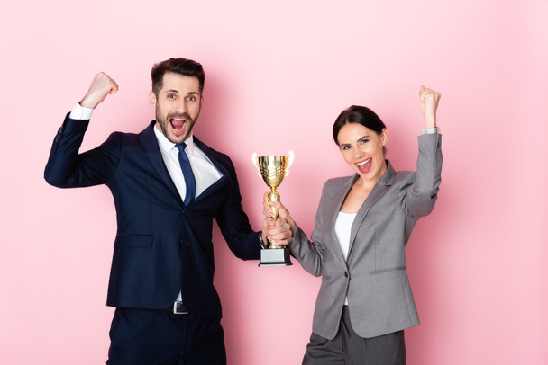 excité homme d'affaires et femme d'affaires tenant trophée et geste sur rose, concept d'égalité des sexes - Photo, image