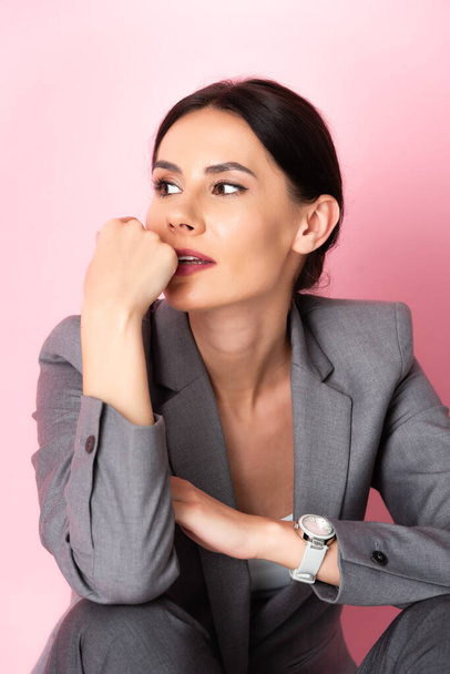 pensive businesswoman in suit looking away isolated on pink  - Foto, Imagem
