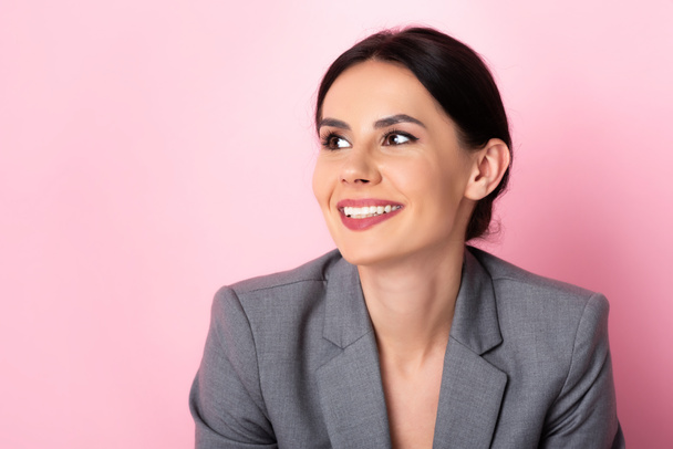 happy businesswoman in suit looking away on pink  - Valokuva, kuva