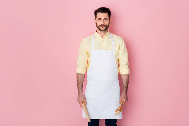 handsome bearded man holding rolling pin and wooden spoon on pink  - Foto, Imagem
