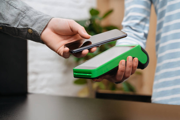 Müşteri, NFC teknolojisini kullanarak akıllı telefon ile ödeme yapıyor. Adam alışveriş yapıyor, mal satın alıyor. Telefonla ulaşılamaz ödemeler yapıyor. Bağlantısız ve NFC teknolojisi - Fotoğraf, Görsel