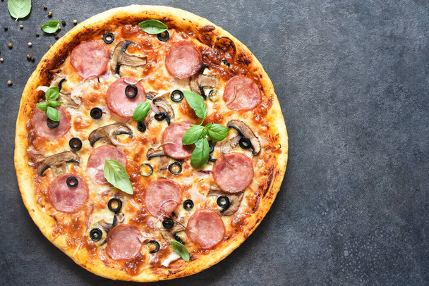 Pizza with salami, mushrooms and tomato sauce on a black background. View from above. - Zdjęcie, obraz