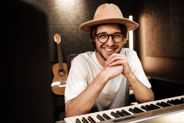 Mladý atraktivní hudebník radostně pracuje na novém hudebním albu v moderním nahrávacím studiu - Fotografie, Obrázek