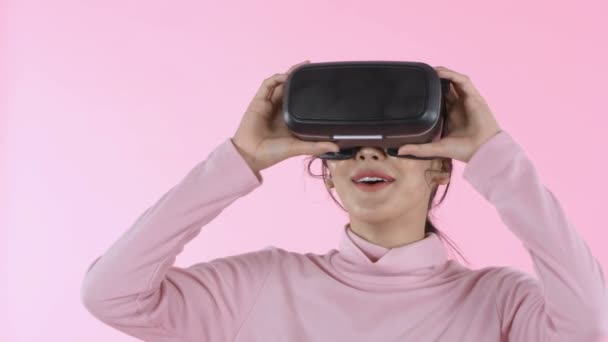 Beauty concept. Smile young woman wearing using virtual reality VR glasses helmet headset on pink background. 4k Resolution. - Πλάνα, βίντεο