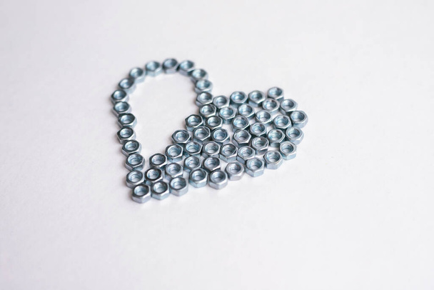 Heart laid out of bolts, nuts on a white background. Fathers Day and wedding anniversary concept. - Photo, Image