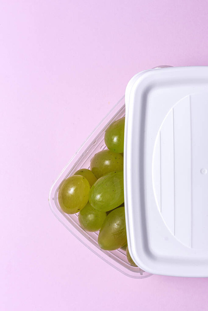 Fresh seasonal grapes in Plastic containers ready to eat To take away. On pink background. Healthy food. Vegan food concept - Foto, imagen
