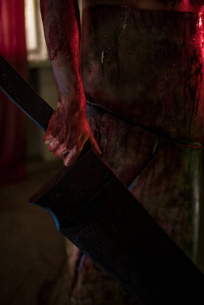 Dnipro, Ukraine - June 27, 2020: Cosplayer in the image of executioner Red Pyramid from the horror movie "Silent Hill" stands in dark room in apron with knife in his hand. Closeup. - Fotó, kép